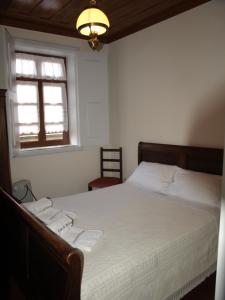 um quarto com uma cama com lençóis brancos e uma janela em Casa de RioBom em Soajo