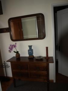 uma cómoda de madeira com um espelho na parede em Casa de RioBom em Soajo