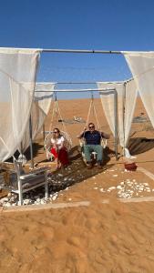 two people sitting in swings on the beach at Stars camp in Al Raka +9 photos