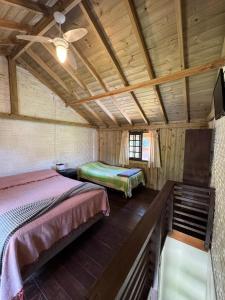 a bedroom with two beds and a ceiling fan at Pousada Vale da Praia in Praia do Rosa