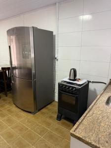 a kitchen with a stainless steel refrigerator and a stove at Chalé 01 centro de itapema 150m do mar in Itapema