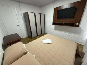 a room with a bed and a flat screen tv at Chalé 01 centro de itapema 150m do mar in Itapema