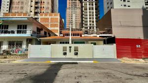 a building with white doors in the middle of a city at Chalé 01 centro de itapema 150m do mar in Itapema