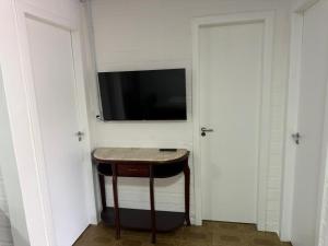 a small table in a room with a tv on a wall at Chalé 01 centro de itapema 150m do mar in Itapema