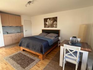 a bedroom with a bed and a table and a kitchen at Panorama-Haus Appartment PFÄNDER - Bergblick, Badezimmer, Kitchenette, eigene Sonnenterrasse in Wangen im Allgäu
