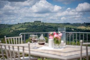 a table with wine glasses and flowers on a balcony at Villa Sunset in Greve in Chianti