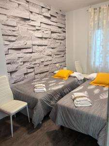 a bedroom with two beds and a stone wall at Los Soportales in Soria