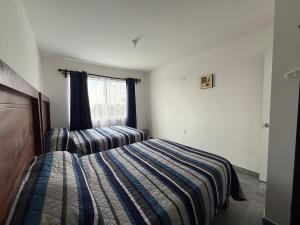 a bedroom with a striped bed and a window at Casa Alejandra, Bernal Pueblo Magico in Bernal