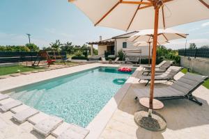 a swimming pool with chairs and an umbrella at KLM holiday home in Rupalj