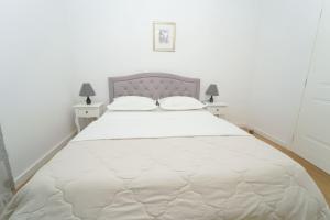 a bedroom with a large white bed with two tables at KLM holiday home in Rupalj +44 photos