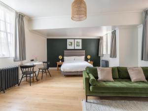 a bedroom with a bed and a green couch at Numa London Chelsea Green in London