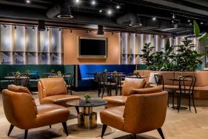 a waiting room with tables and chairs and a tv at Corendon Urban Amsterdam Schiphol Airport Hotel in Badhoevedorp