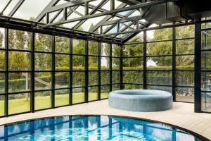 a swimming pool in a glass house with a view at Corendon Urban Amsterdam Schiphol Airport Hotel in Badhoevedorp +22 photos