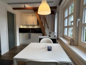 a kitchen with a white table and chairs and windows at Lütthüs Blankenese in Hamburg