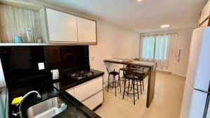 a kitchen with a counter and stools in a room at Chalé 02 centro de itapema in Itapema