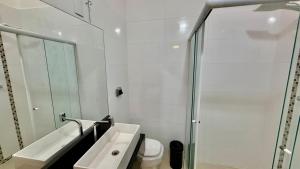 a bathroom with a sink and a toilet and a mirror at Chalé 02 centro de itapema in Itapema +3 photos