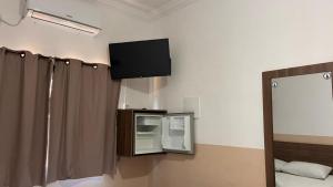 a room with a tv on the wall and a mirror at Pousada Bela Rainha in Aparecida