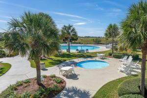 a pool with palm trees and tables and chairs at Harbor Island 49 Nautical Watch in Fripp Island