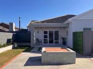 a white house with a bench in the front yard at The Shirley in Gqeberha