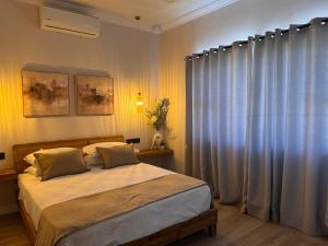 a bedroom with a bed and a window with curtains at The Shirley in Gqeberha