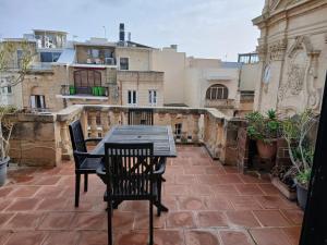 a table and chairs on a patio with buildings at Gozo Duplex Studio overlooking historic Piazza in Victoria