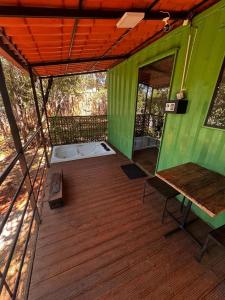 a green house with a bed on a wooden deck at Cipó Container in Santana do Riacho +2 photos
