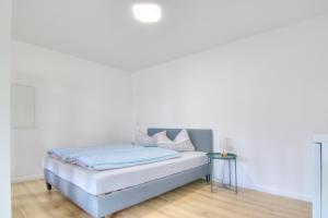a white bedroom with a bed and a table at Modernes Wohlfühl-Apartment mit Glasfaser-WLAN, Parkplatz in der Nähe & Küche in Bad Wimpfen in Bad Wimpfen