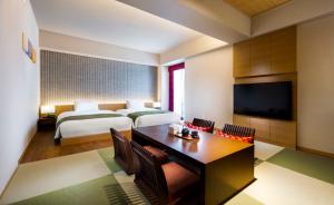 a hotel room with a bed, table, television and a lamp at RIHGA Royal Hotel Kyoto in Kyoto