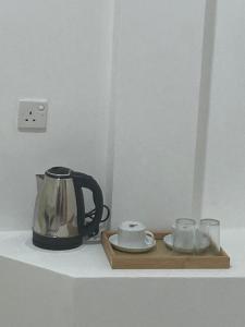 a tea kettle and two cups on a shelf at TENBY Guest House in Anuradhapura