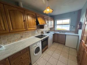 a kitchen with wooden cabinets and a sink and a dishwasher at Portmagee Seaside Cottages - Gannet in Portmagee +7 photos