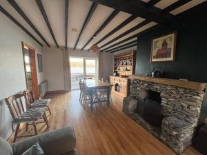 a living room with a stone fireplace and a table and chairs at Portmagee Seaside Cottages - Gannet in Portmagee
