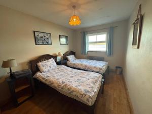 a bedroom with two beds and a window at Portmagee Seaside Cottages - Gannet in Portmagee