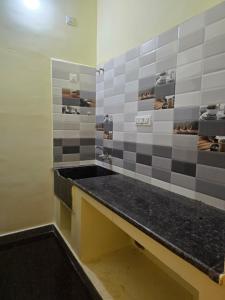 a bathroom with a black counter and gray tiles at Yercaud Misty Haven in Yercaud