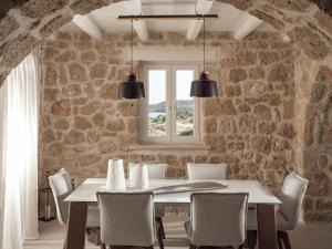 a stone walled dining room with a table and chairs at Astarte Villas - Arismari Villas in Vasilikos
