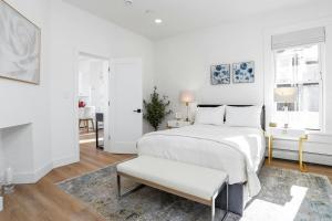 a white bedroom with a bed and a chair at Harbor Haven, Apt #5, 3BR/2BA in Stamford