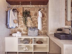a bathroom with a sink and a shelf with towels at Astarte Villas - Arismari Villas in Vasilikos +73 photos