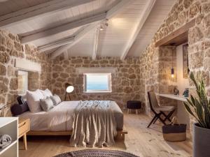 a bedroom with a bed and a stone wall at Astarte Villas - Arismari Villas in Vasilikos
