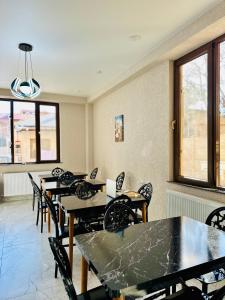 a dining room with tables and chairs and windows at City Star Kutaisi in Kutaisi