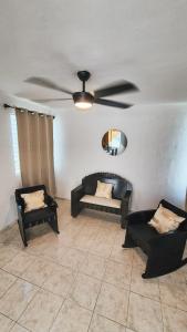 a living room with a ceiling fan and two chairs at Casa Amplia San Pedro Norte Cerca Fco Montejo in Mérida