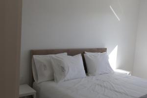 a bed with white pillows and a white wall at Casa do Santo Estevão in Macedo de Cavaleiros +10 photos