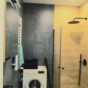 a bathroom with a washing machine in a room at Klonowicza One in Leszno +3 photos