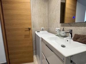 a bathroom with a sink and a wooden door at Sweet Dreams Apartment, estilo y confort en 1ª línea, Renovado, Práctico y Anfitrión 5 Estrellas" in Empuriabrava