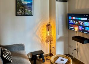 a living room with a couch and a flat screen tv at O coeur de l'ouest Bungalow Maloya in Le Bois de Nèfles