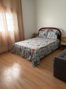 a bedroom with a bed with a bedspread and a couch at Pousada Jardim Alterosa in Vespasiano