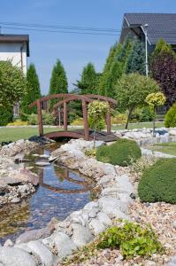 un puente de madera sobre un arroyo en un jardín en Zajazd Tytan, en Kochanowice