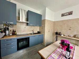 a kitchen with blue cabinets and a table with flowers at Ziva's house apartment in Abbiategrasso in Abbiategrasso
