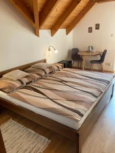 a large bed in a room with a table and chairs at Penzion Úsmev in Arnutovce