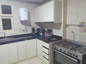 a small kitchen with a stove and white cabinets at سي فيو سان ستفانو in Alexandria