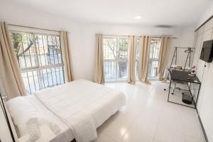 a white bedroom with a bed and a tv and windows at Alicante Beach Hostel in Alicante