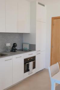 a kitchen with white cabinets and a stove at Casa Refúgio da Natureza in Macedo de Cavaleiros